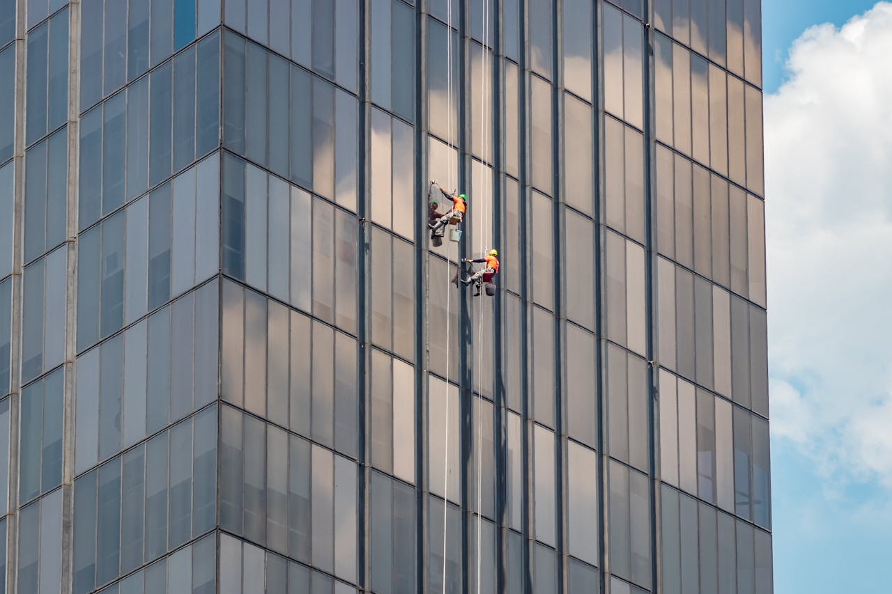 Two window cleaners working on a modern office building in Ciudad de México.